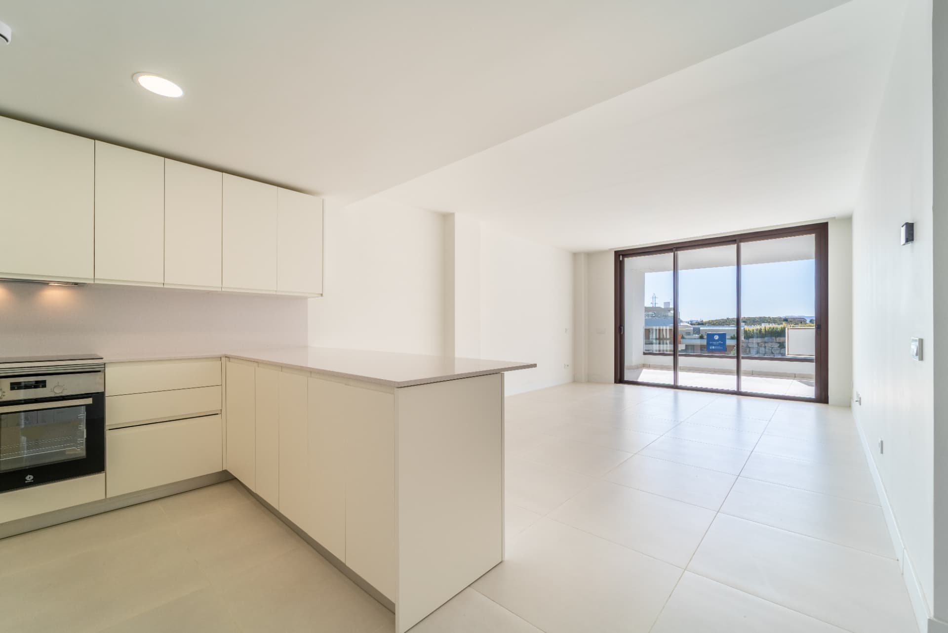 Unfurnished bright kitchen and living space opening onto a wide terrace