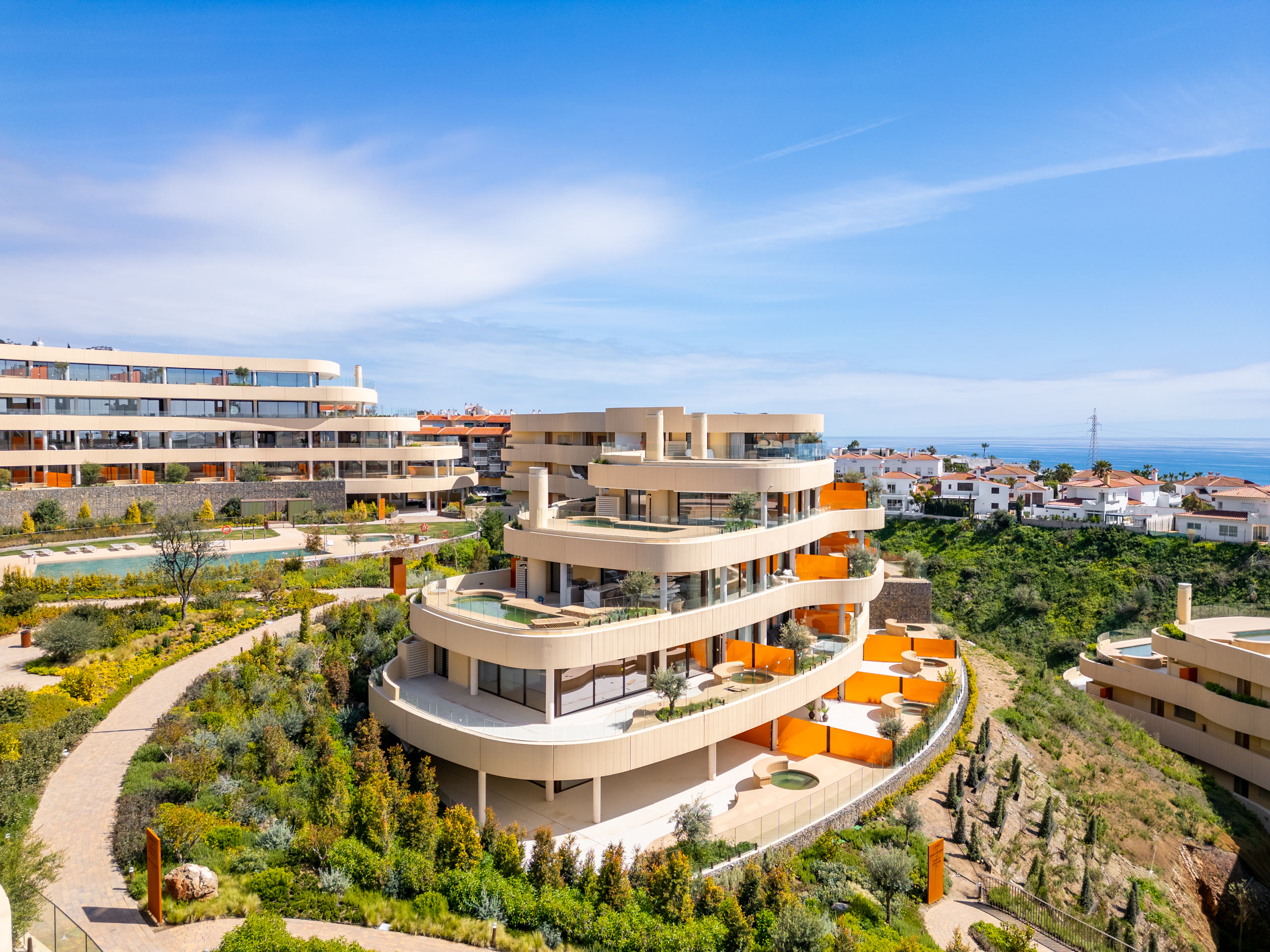 Aerial view of curved Mediterranean apartment terraces with private pools above the sea